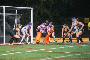 Field hockey players competing near goal during a night match.