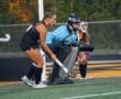 Field hockey players ready in defense during a match, focused and prepared near the goal.