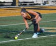 Field hockey player in action, skillfully hitting the ball on a turf field.
