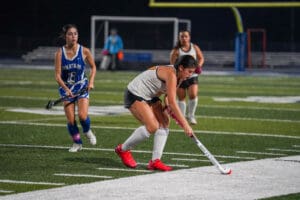 Field hockey players competing in a night match on the field.