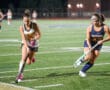 Field hockey players in action during a nighttime match, showcasing skills on a well-lit turf field.