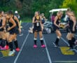 Field hockey team warming up with footwork drills on a track.