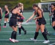 Girls' field hockey team practicing on the field, players preparing for a game.