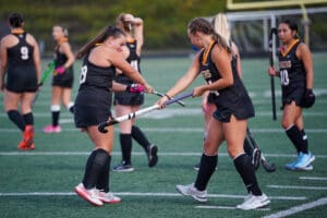 Girls' field hockey team practicing on the field, players preparing for a game.