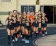 Girls' field hockey team jogging on track, wearing black uniforms. Team spirit and fitness training concept.