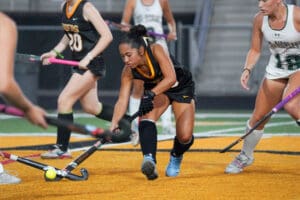 Female field hockey players in action during a competitive match, focused on the ball.