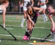 Field hockey players compete for the ball on a turf field during an exciting match.