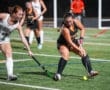 Field hockey players in action during a competitive match, focused on controlling the ball on the field.