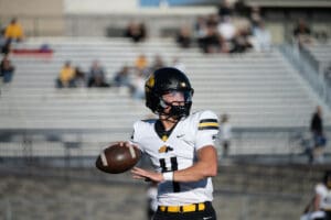 Football player in action, preparing to throw a pass during a game on a bright, sunny day.