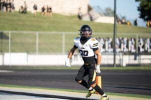 Football player on field wearing black and white uniform during a sunny game day.