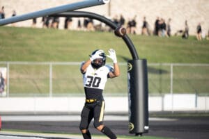 Football player in black and yellow jersey catching a ball near end zone.