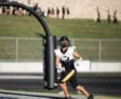 Football player running into the end zone during a game, wearing a black and white uniform and helmet.