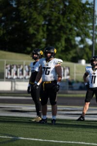 High school football players in uniform and helmets standing on the field ready for a game.
