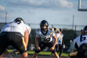 Football players on a sunny day, preparing for a play on the field in full gear and uniforms.