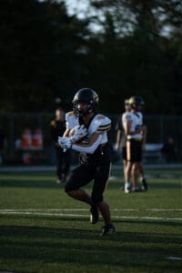 Football player in black and white uniform running on the field during a game.