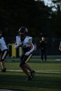 Football player running with ball during game under dim lighting.
