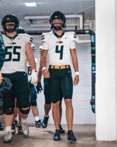 Football players in uniform walking through a tunnel, preparing for a game.