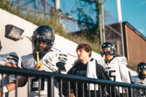 Football players in uniform walking onto the field, preparing for a game, sunny day.