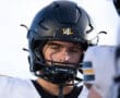 Young football player in black helmet and white jersey focused before the game.