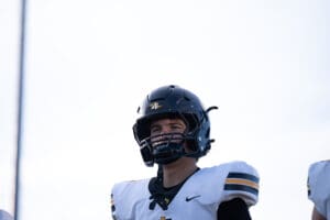 Football player in a black helmet and white jersey looking determined during a game.