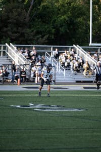 Football player in action on the field during a game, with spectators in the background.