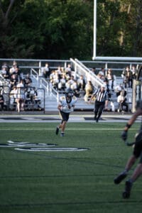 Football player running on field with audience in background, focused on making a play.