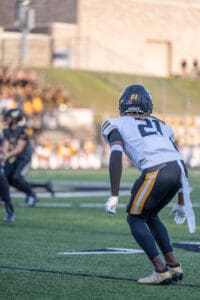 Football player on field, wearing number 21 jersey, ready to defend during game.