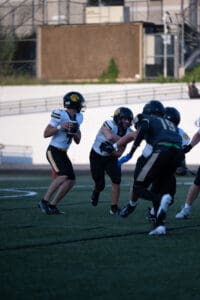Football quarterback ready to pass during a game with teammates blocking opponents.