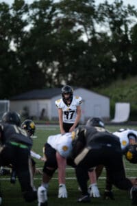 Football quarterback preparing play during a game with players on the line of scrimmage.