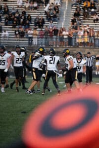 Football players celebrating after a successful play on the field, crowd cheering in the background.