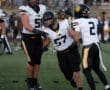 Football players in black and yellow uniforms celebrating a successful play on the field.