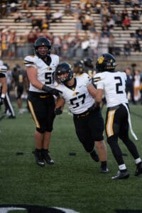 Football players in black and yellow uniforms celebrating a successful play on the field.