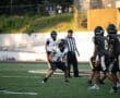 High school football players in action with a referee on the field, preparing for play.