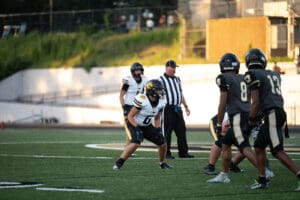High school football players in action with a referee on the field, preparing for play.