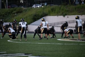 Football players in formation on a field during a game at dusk.