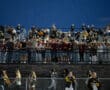 Crowd of enthusiastic fans in stadium bleachers during a nighttime sports event, enjoying the live action.