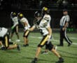 High school football player on field giving thumbs-up during night game.