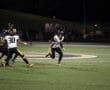 Football player in action during a night game, running with the ball on a lit field.