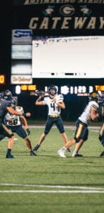 Football quarterback preparing to throw during a night game at Gateway Stadium.