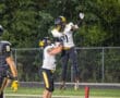 Football players celebrate a touchdown with a jump hug on the field at night.