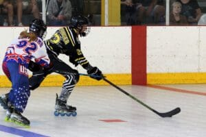 Roller hockey players in action on the rink, wearing colorful gear and focused on the puck.