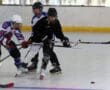 Three players in action during a roller hockey game, battling for the puck on a rink.