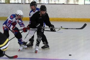 Three players in action during a roller hockey game, battling for the puck on a rink.