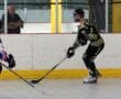 Two roller hockey players in action during a match in an indoor rink.
