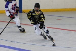 Hockey players compete in an indoor rink, focusing on maneuvering the puck during a game.