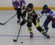 Youth roller hockey game in action with players competing for the puck on the rink.