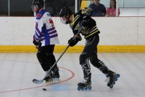 Inline hockey players in action on rink, focused on puck control and speed.