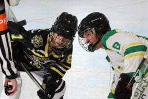Two hockey players face off on the rink as the referee prepares to drop the puck during an intense ice hockey match.