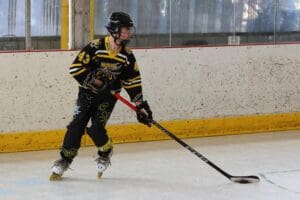 Hockey player in black and yellow jersey holding a stick during a game on an ice rink.