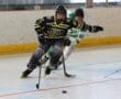 Two hockey players competing intensely on the ice rink, focused on the puck during a fast-paced game.